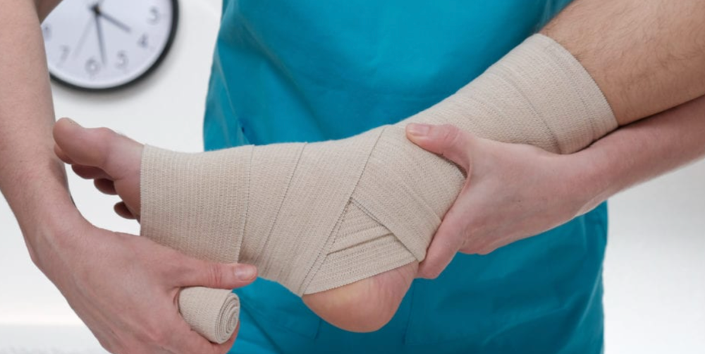Physiotherapist assessing a patient's swollen ankle after a sprain